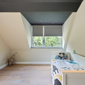 Modernes Kinderzimmer im Dachgeschoss mit Holzfußboden, Einzelbett und Kuscheltieren.