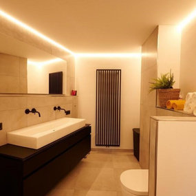 Modernes Badezimmer mit großem Spiegel, LED-Beleuchtung und stilvollem Waschtisch.