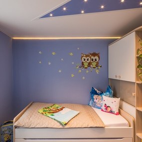 Modernes, liebevoll dekoriertes Kinderzimmer mit Eulen-Wandtattoo, Pflanzen und Kuscheltieren.